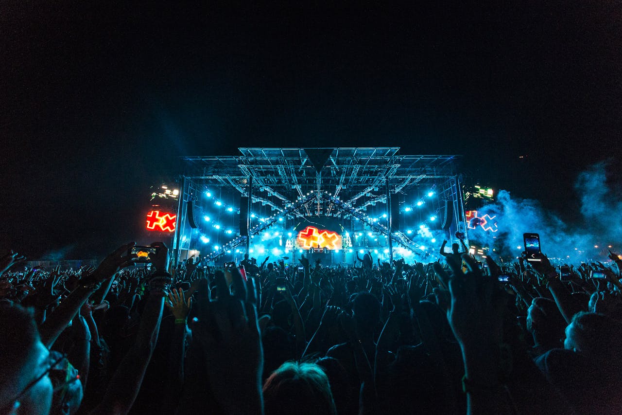 Vibrant crowd enjoying an epic concert under bright stage lights with smoke effects.